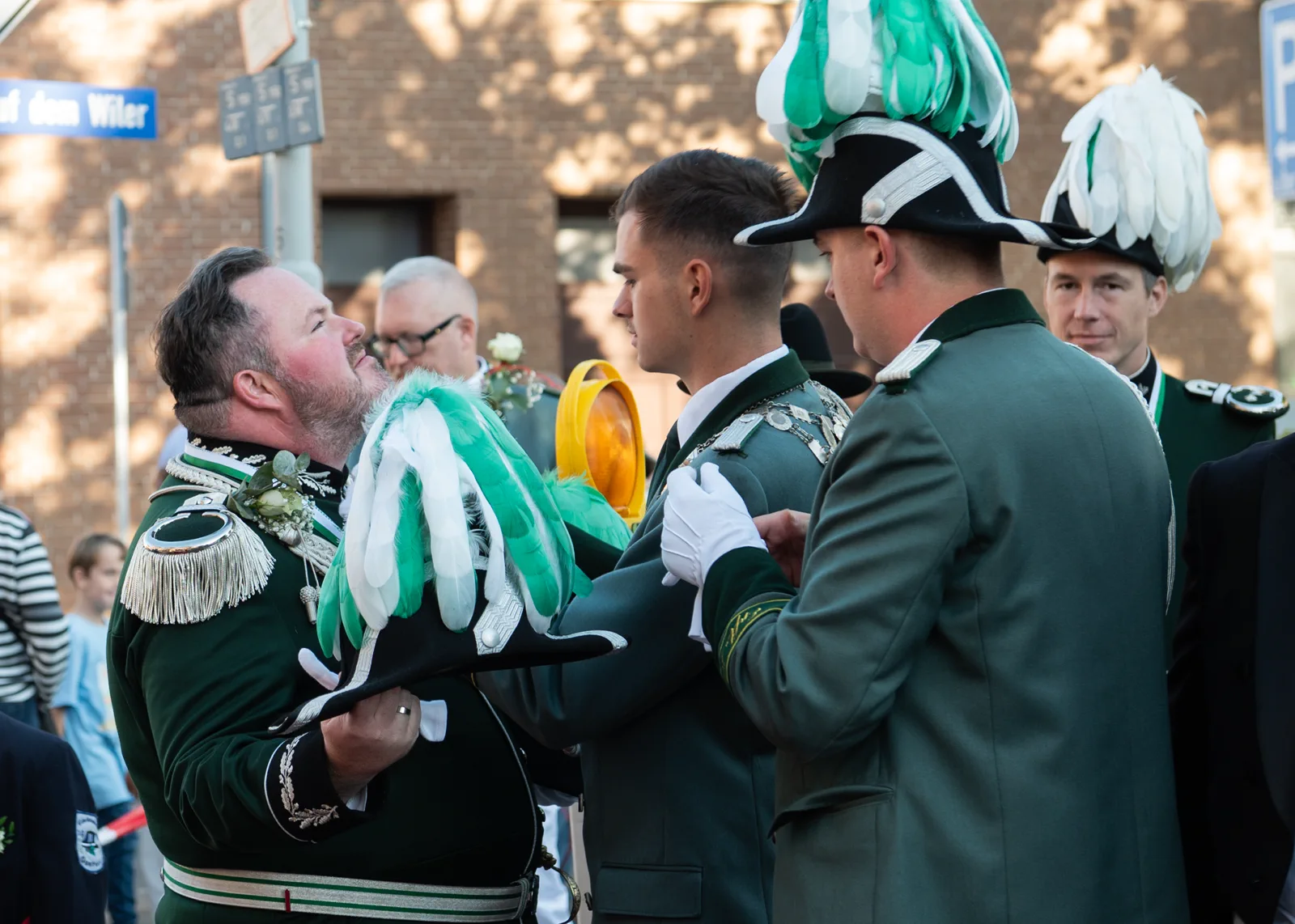 Schützen in grünen Uniformen begrüßen sich am Zugweg.